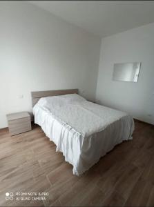 a white bedroom with a bed and a wooden floor at Tropical House in Formia