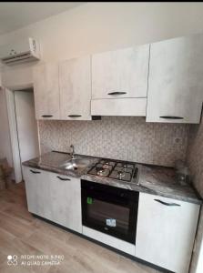 uma cozinha com armários brancos, um fogão e um lavatório em Tropical House em Formia