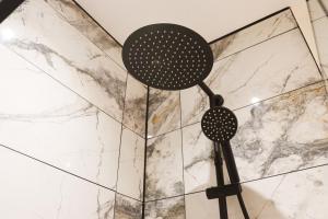 a pair of shower heads in front of a marble wall at Mood Apartment 4 in Bedlington