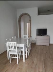 mesa de comedor con sillas blancas y TV en Tropical House, en Formia