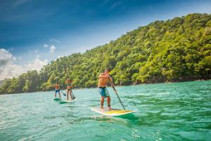 three people are paddle boarding on the water at Los Suenos Resort Casa Puesta del Sol by Stay in CR in Herradura
