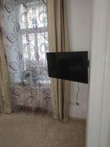 リヴィウにあるУютная квартираのカーテン付きの客室内の薄型テレビ