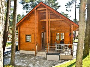 a small wooden cabin with a table and chairs at Four -anniversary Type B in Dźwirzyno
