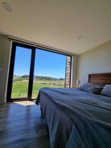 a bedroom with a large bed and a large window at Casa de campo familiar, Puerto Varas Chile in Llanquihue