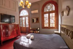 a bedroom with a bed and a tv and two windows at Play Hostel Arcos in Buenos Aires