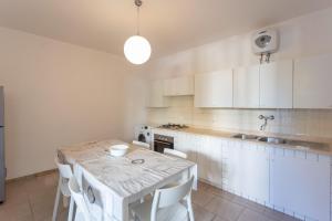 una cucina con mobili bianchi, tavolo e sedie di Casa Vacanze Sole by Casavacanze di Angelo a Porto Cesareo