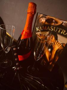 eine Flasche Wein neben zwei Gläsern und eine Zeitschrift in der Unterkunft World Of Ecstasy - Apartament BDSM in Reda