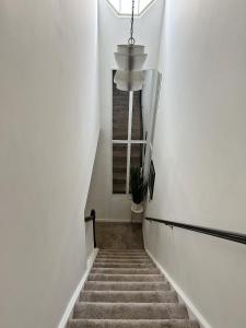 a staircase with a chandelier in a white hallway at Beautiful loft style townhouse-vaulted ceilings in Romeoville
