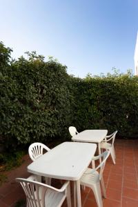 2 tavoli e sedie bianchi seduti su un patio di Casa Vacanze Sole by Casavacanze di Angelo a Porto Cesareo