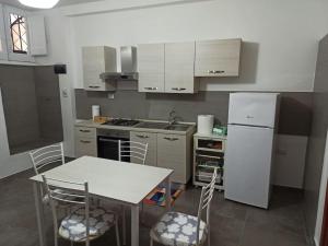 een keuken met een tafel en een witte koelkast bij Intero alloggio - centro storico - La Tana di Aldo- 150 m da Pepe in Grani in Caiazzo