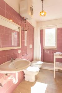 un bagno rosa con lavandino e WC di Casa Vacanze Sole by Casavacanze di Angelo a Porto Cesareo