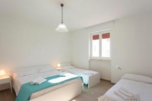 una camera da letto bianca con due letti e una finestra di Casa Vacanze Sole by Casavacanze di Angelo a Porto Cesareo Altre 15 foto