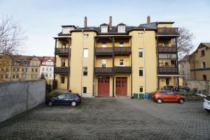 a large yellow building with two cars parked in front at Retreat am Teich in Altenburg