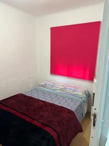 Habitación pequeña con ventana roja y cama en Apartamento,Albares de la Ribera en Madrid