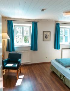 1 dormitorio con cortinas azules, 1 cama y 1 silla en Hotel-Restaurant am Schloss Kronwinkl, en Eching