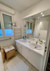 un bagno con due lavandini e un grande specchio di Grand appartement lumineux près de Paris a Le Plessis-Robinson