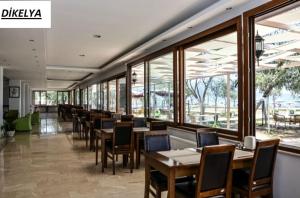 a dining room with tables and chairs and windows at Dikelya Hotel in Dikili