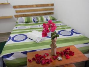 uma cama com um vaso com flores sobre uma mesa em HostalNativo em Taganga