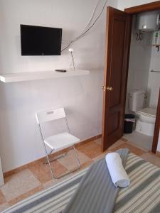 sala de estar con TV y silla en Pensión Montero, en Jedula