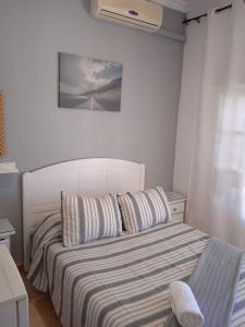 1 dormitorio con 1 cama con colcha a rayas en Pensión Montero, en Jedula