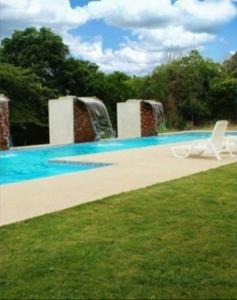 een zwembad met een witte stoel in het gras bij PLAYA Y CAMPO EN UN SOLO LUGAR in Olón