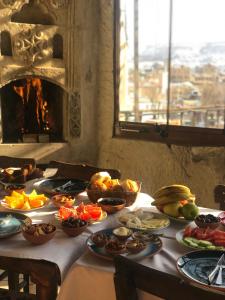 a table with plates of food on it with a fireplace at Kismet Cave House in Goreme