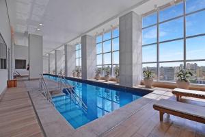 a large swimming pool in a building with windows at Osasco Piscina aquecida Vista Estacionamento in Osasco