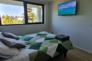 a bedroom with a bed and a tv on the wall at Depto. nuevo con hermosa vista in Valdivia