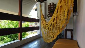 a hanging hammock in a room with a window at Pousada Du’Forte in Praia do Forte