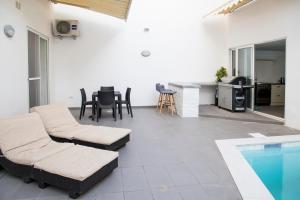um pátio com uma piscina, uma mesa e cadeiras em Apartment with luxurious pool 5 mins walk from the beach em Naxxar