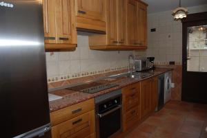 uma cozinha com armários de madeira e um forno com placa de fogão em Casa Rural "Los Herrero" em Zarzuela del Monte