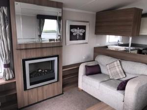 a living room with a couch and a fireplace at 3 BEDROOMED CARAVAN WITH AMAZING SEA VIEWS! in Scarborough