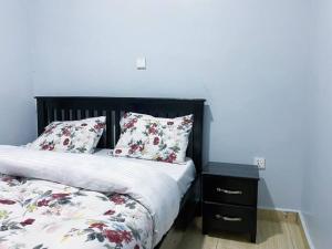 um quarto com uma cama com almofadas florais e uma mesa de cabeceira em 3bedrooms Home in Musanze em Cyuve