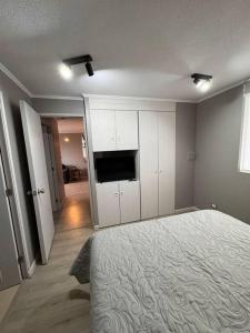 a bedroom with a bed and a flat screen tv at Moderno Departamento in Osorno