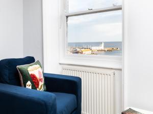 Sofá azul en una habitación con ventana en Waimea Apartments - Sea Views South Bay Scarborough Free Parking en Scarborough