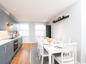 a kitchen with a white table and white chairs at Waimea Apartments - Sea Views South Bay Scarborough Free Parking in Scarborough
