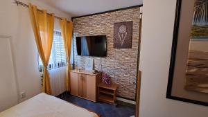 a small bedroom with a brick wall and a television at Red blue with private parking and Gray blue apartment in Pula