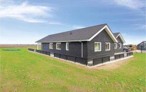 a black house on a large grass field at Amazing Home In Bogense With Sauna in Bogense +22 photos