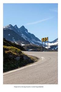 una strada vuota con un cartello sul fianco di una montagna di Turtagrø Hotel a Fortun