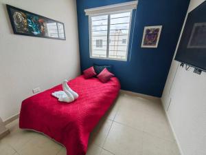 a bedroom with a red bed with a white swan on it at Casa Meraki in Querétaro