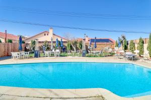 una piscina con sillas, mesas y sombrillas en Palmdale Family Home with Private Pool and Backyard en Palmdale