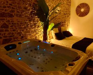 a bath tub in a room with a bedroom at Profitez d'une douce nuit avec jacuzzi in Fougères