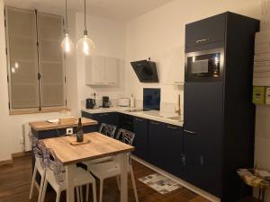 a kitchen with a wooden table and a black refrigerator at Profitez d'une douce nuit avec jacuzzi in Fougères