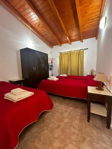 Cette chambre comprend 2 lits avec des draps rouges et une table. dans l'établissement Cabañas el Pinar, à Huerta Grande 34 autres photos