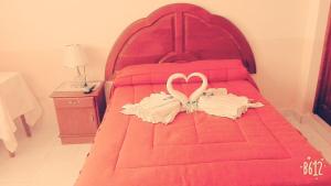 een rood bed met twee handdoeken in hartvorm bij HOTEL IDEAL in Villazón