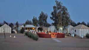 a group of tents in a field with lights at Berber Camp in Merzouga