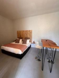 a bedroom with a bed and a wooden table at Studio Zen in Cape Town