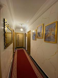 a hallway with a red carpet and paintings on the wall at Appartement meublé Tanger in Tangier