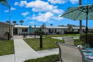 a patio with a table and chairs and an umbrella at Jamaica Royale Beach Happiness in Siesta Key