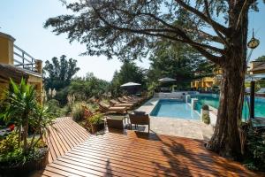 una terraza de madera junto a una piscina con un árbol en Las Princesas Cabañas en Los Reartes